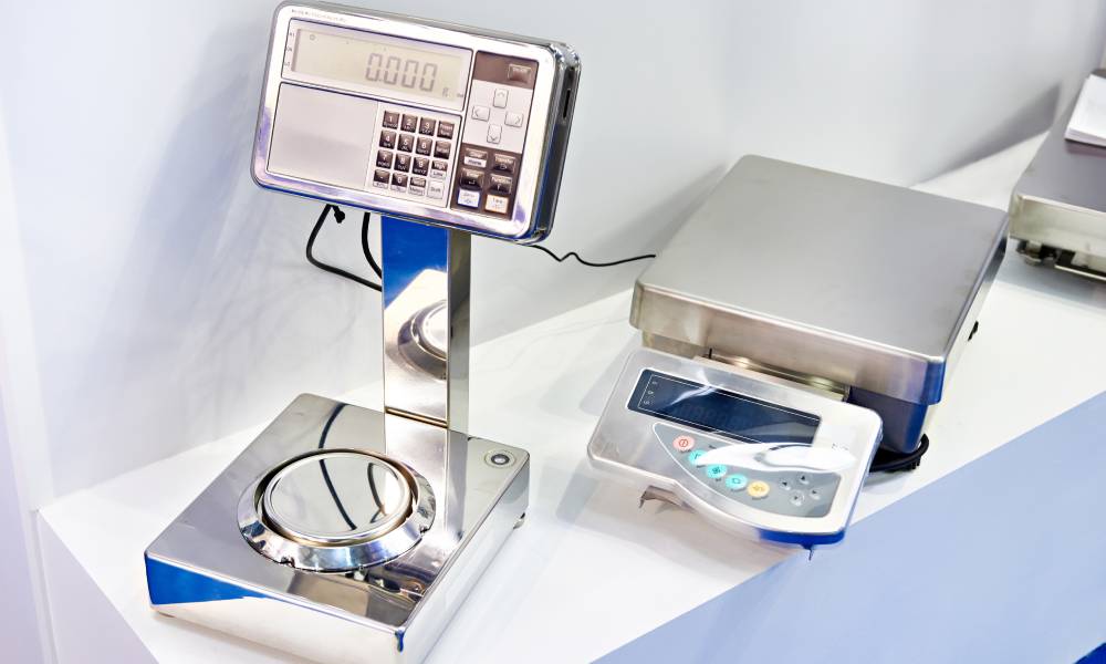 close up of two benchtop scales with digital displays made of stainless steel on top of a white counter next to a white wall