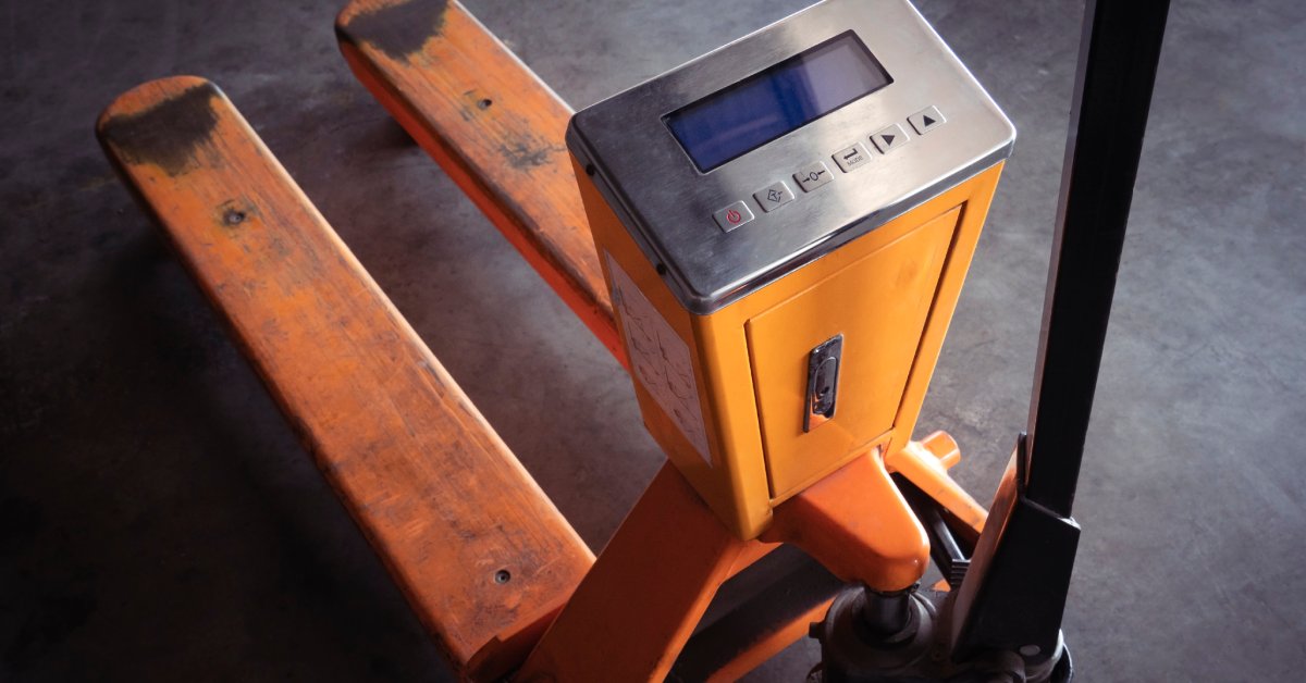 An overview of an orange industrial pallet truck or manual hand lift with checkweigh digital scales.
